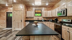 Une cuisine dotée de meubles en bois, d’un îlot central, d’un four à micro-ondes et d’une cuisinière.
