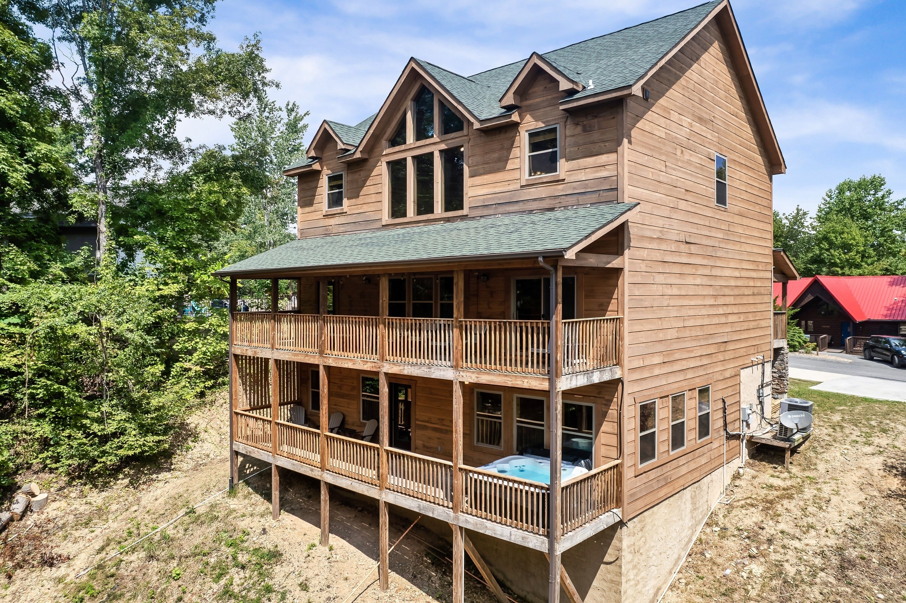 Eine zweistöckige Holzhütte mit Balkon, Whirlpool und überdachter Veranda.