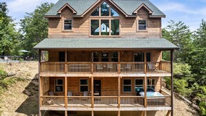 Une maison en bois à deux étages, dotée d’un balcon au rez-de-chaussée et d’une grande fenêtre à l’étage supérieur.