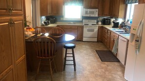 Una cocina compacta con armarios de madera, una estufa blanca, un microondas y un lavabo.