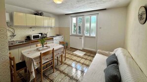 A compact kitchen with a dining area, a sofa, and a window. - Holiday apartment with terrace and air conditioning (Dramalj)