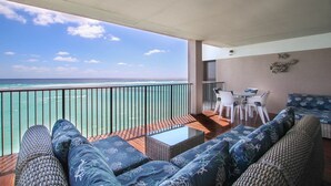 A balcony with a view of the ocean, wicker furniture, and a small table. - Beachfront Luxury with Incredible Ocean Views (Worthing)