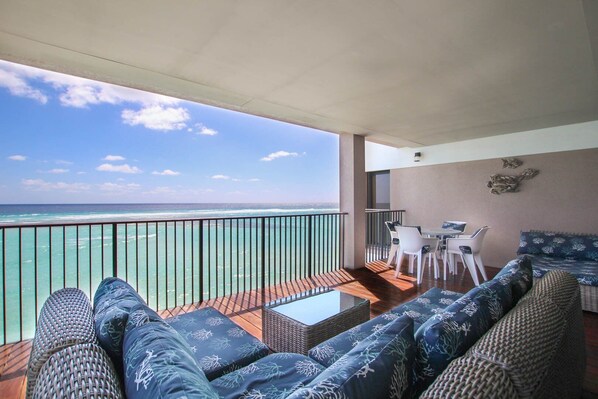 A balcony with a view of the ocean, wicker furniture, and a small table. - Beachfront Luxury with Incredible Ocean Views (Worthing)