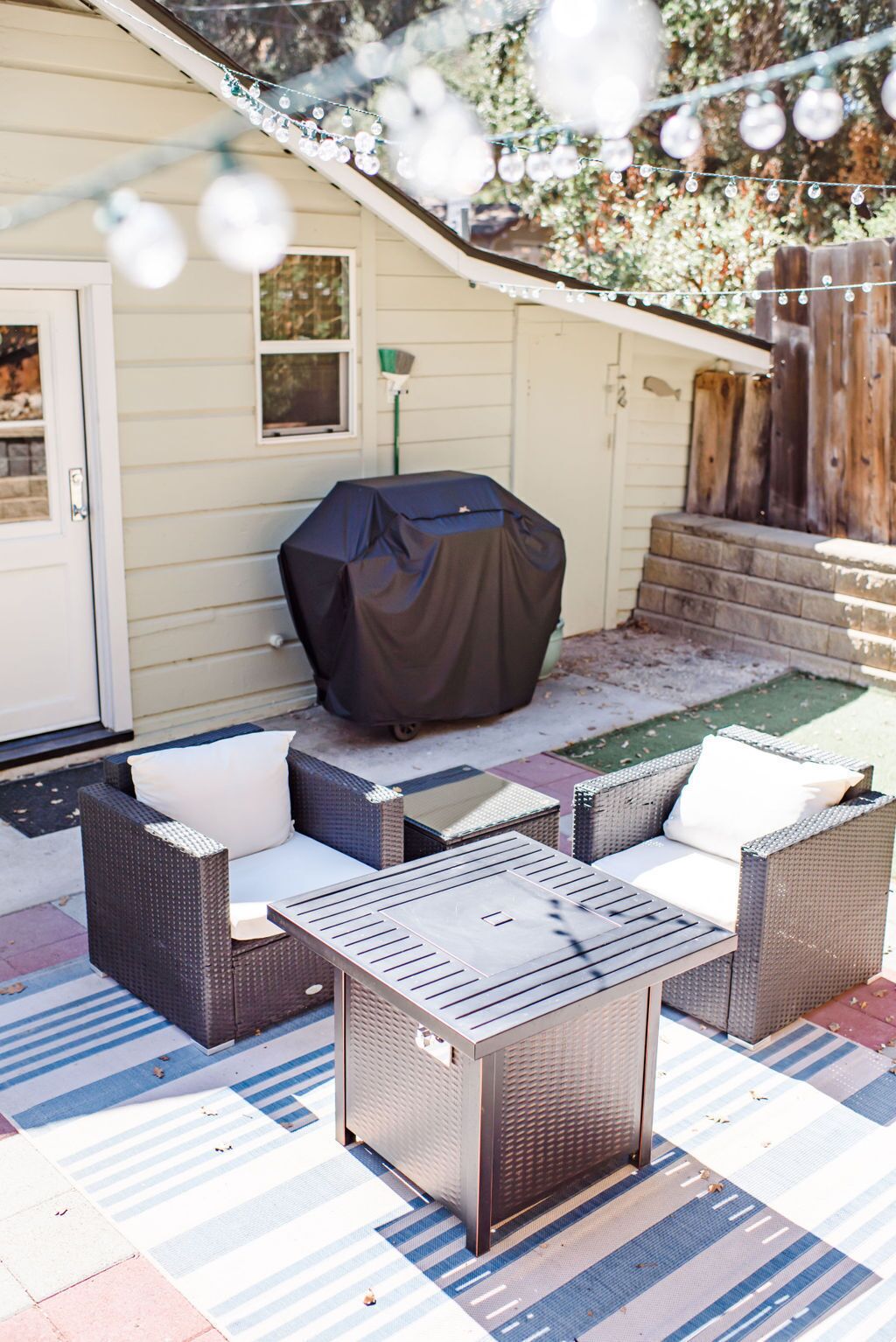 An outdoor patio with wicker furniture and a covered grill.