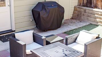 An outdoor patio with wicker furniture and a covered grill.