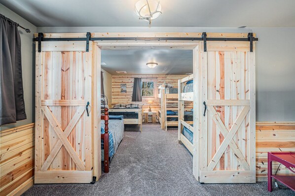 A room with a bed, a small table, and a bunk bed. - Large LODGE•Sleeps 20• Game Rm •HOT TUB• Golf nearby • Pontoon • poker rm (Lawrence)