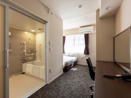 Una habitación de hotel con ducha, cama, escritorio y silla.