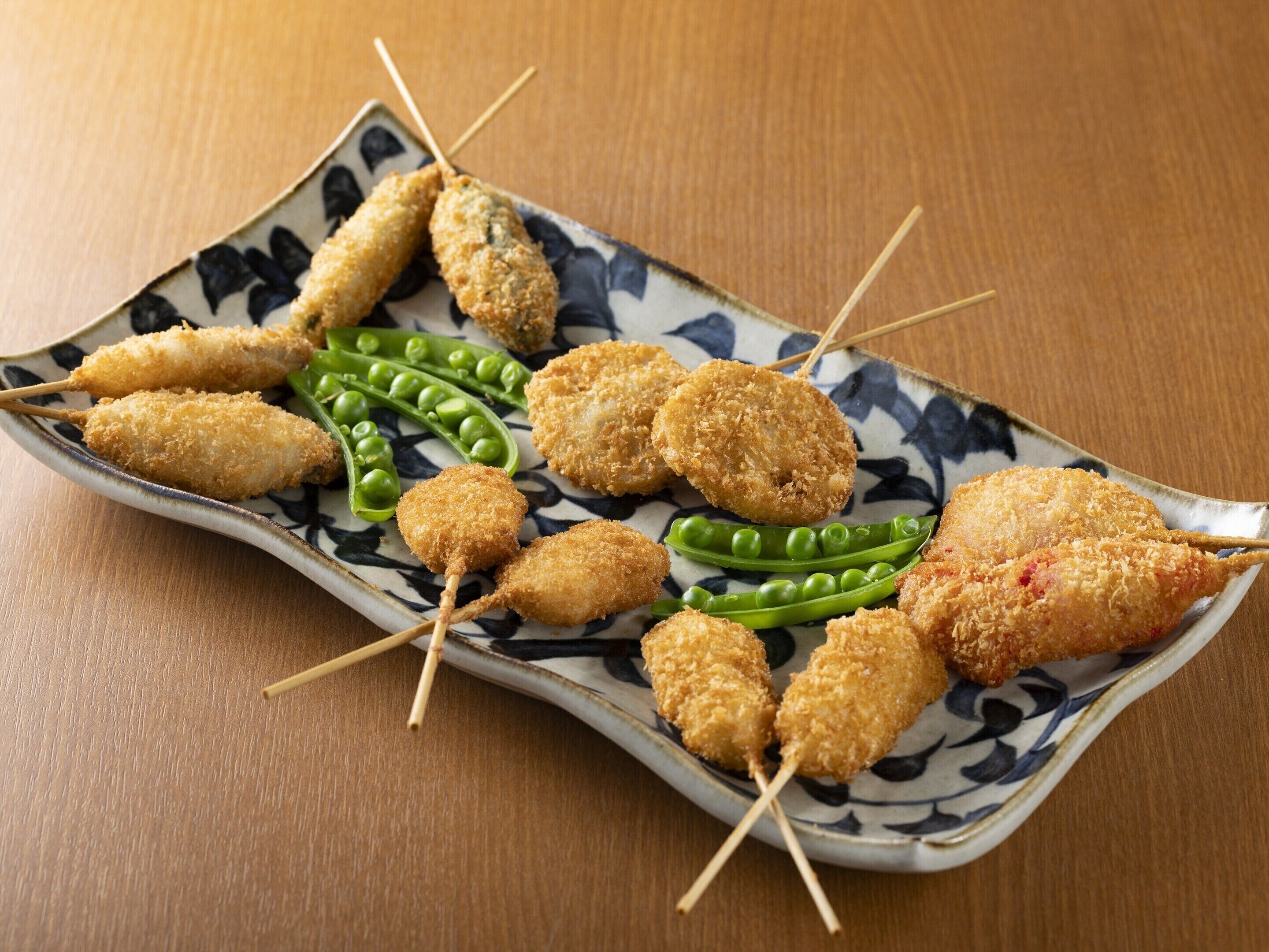 A plate of fried food items with peas.