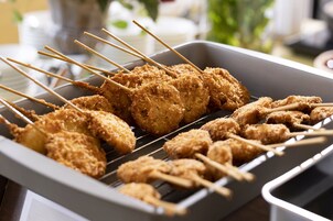 Espetinhos de comida empanada na grelha.