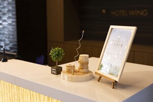 Un mostrador de recepción con una pequeña planta en maceta, una pila de bloques de madera y un mapa enmarcado.