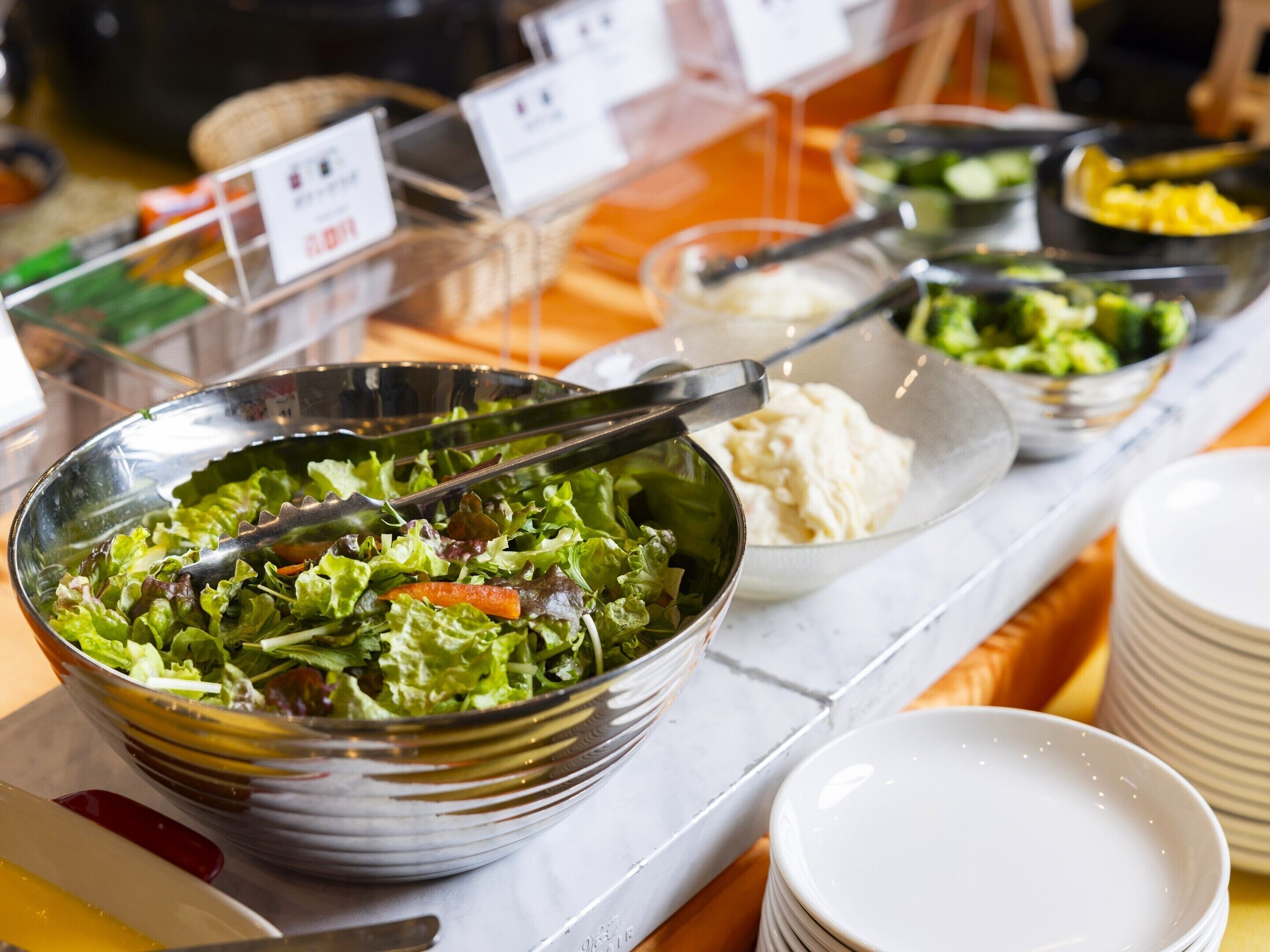 A buffet table with various dishes, including a large bowl of salad and several other dishes in separate containers.