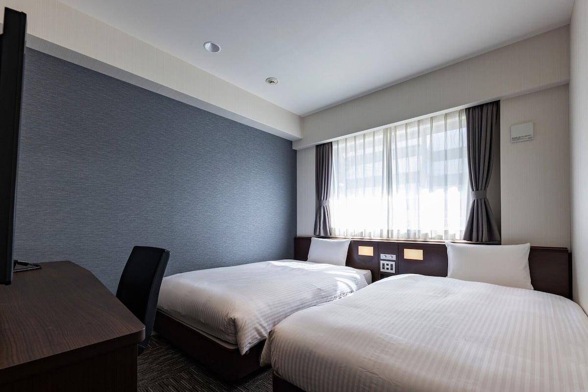 Una habitación de hotel con dos camas, un escritorio y una silla.
