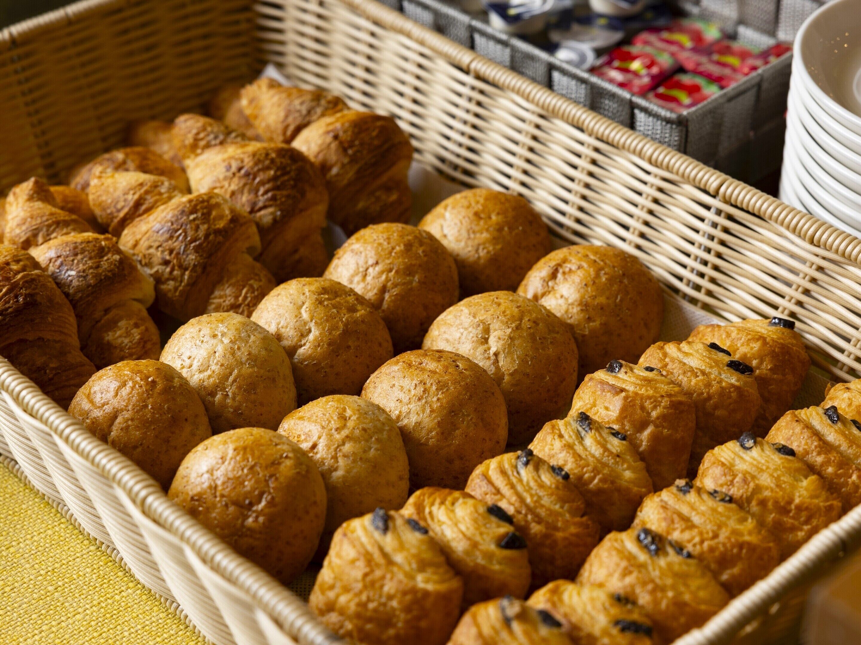 Una cistella de viquern plena de diversos productes de forneria, incloent pa de vidre i croissants.