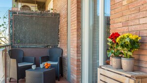 Een terras met rieten meubels, een klein tafeltje met mandarijnen, en potplanten.