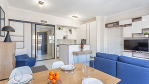 Een moderne woonkamer met een eethoek, een keuken en een televisie.