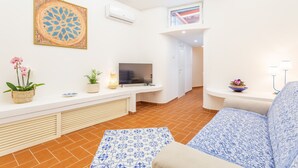 Una sala de estar moderna con un televisor de pantalla plana, un sofá, un tapete estampado y un adorno de pared.