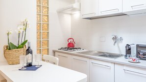 Una cocina moderna con armarios blancos, una estufa a gas, un hervidor y un lavabo.