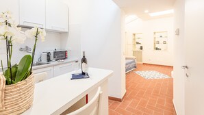 Una cocina moderna con armarios blancos, una encimera y un comedor. Hay una planta sobre la encimera y un microondas.