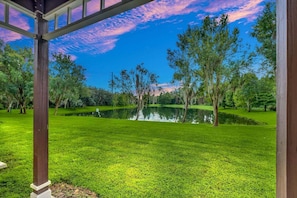 A tranquil park with a pond, trees, and a gazebo structure.