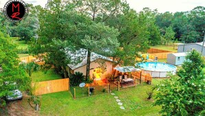 A residential backyard with a swimming pool, a hot tub, and a covered patio area.