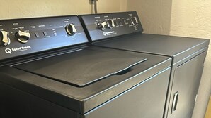 A black front-loading washer and dryer unit with control knobs and a power cord plugged in.