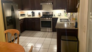 A kitchen with dark wooden cabinets, stainless steel appliances, and a tiled floor.