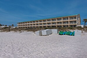 Un hotel de varios pisos con balcones, situado en una playa de arena.