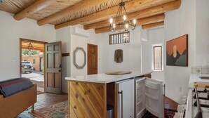 A compact kitchen with a wooden island, a built-in refrigerator, and a hanging light fixture.
