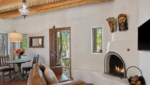A cozy living room with a fireplace, a sofa, and a dining area with a table and chairs.