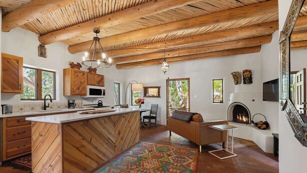 A rustic kitchen with wooden beams, a large island, and a fireplace.