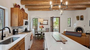A kitchen with wooden cabinets, a white countertop, a stove, a sink, and a chandelier.