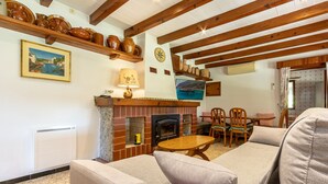 A cozy living room with a fireplace, wooden beams, and rustic decor.