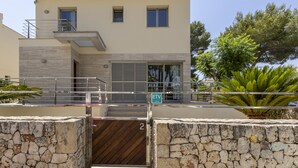 A two-story building with a stone facade, a balcony, and a gate with a number '2'. - Villa Albufera en Playa Muro by Mallorca North Villas (Platja de Muro)