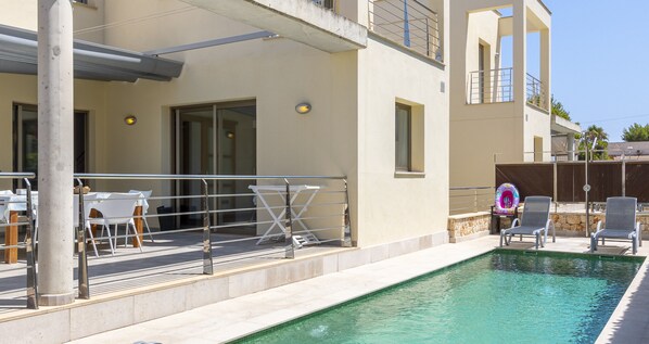 Un espace piscine doté d’une terrasse ensoleillée, de coins salon extérieurs et d’une vue sur la piscine.
