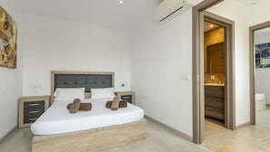 Un dormitorio moderno con una cama de madera, una mesita de noche y una puerta abierta que da a un baño.