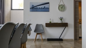 Un comedor con una mesa, sillas, un reloj y una pintura de un paisaje urbano.