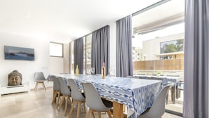 Un comedor con una mesa dispuesta para cuatro personas, una estatua de Buda y un cuadro de una escena costera.