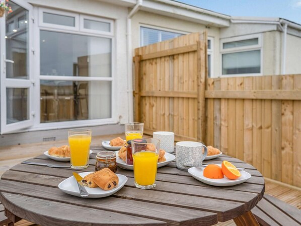 A wooden table with breakfast items including croissants, orange juice, and a mug.