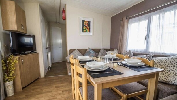 A compact living space with a dining area, kitchenette, and seating area. - Caravan - Sleeps 10 - Pet friendly - Parking (Clacton-on-Sea)
