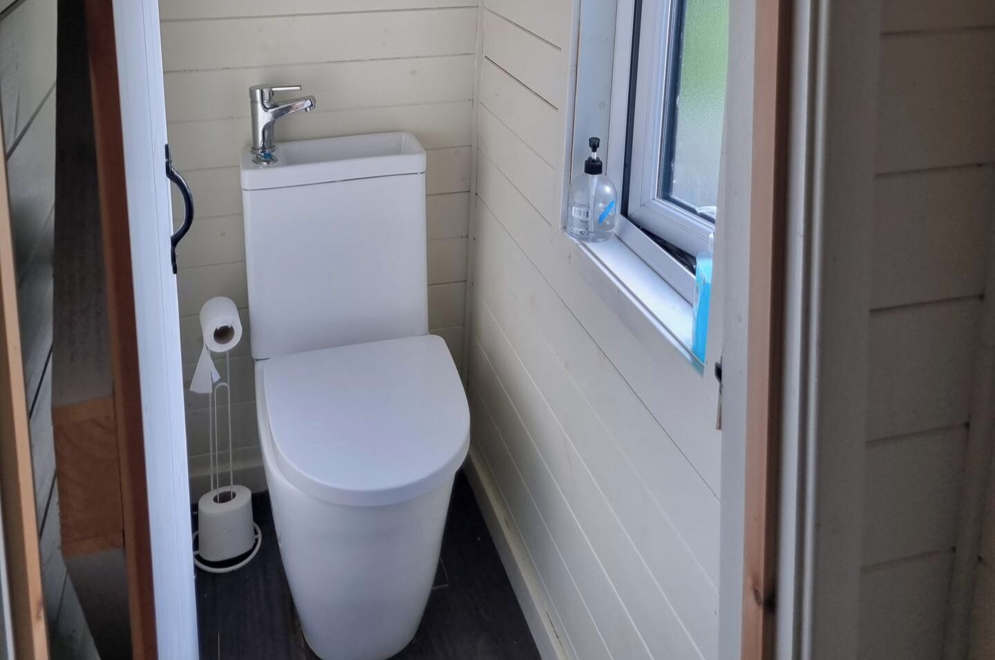 A small, compact bathroom with a white toilet, a sink, and a window.