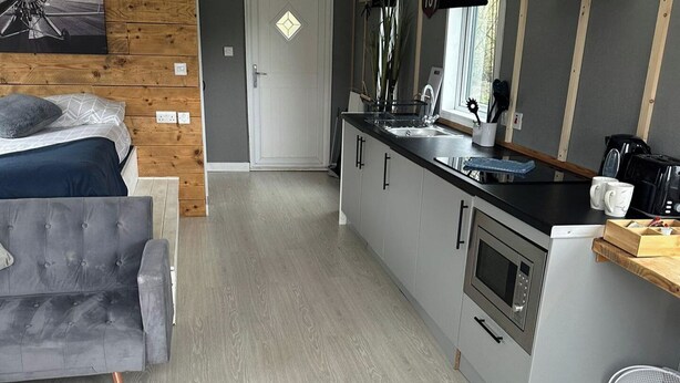 A compact kitchen with a modern design, featuring a built-in oven, a sink, and a coffee maker. - Glamping Hut - Sleeps up to 4 Hot Tub & Parking (Welshpool)