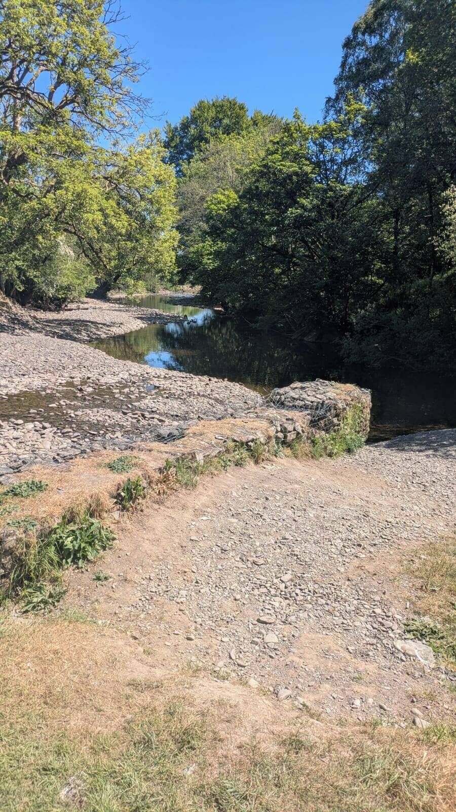 A natural landscape with a river, rocky terrain, and dense trees.