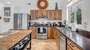 A modern kitchen with wooden cabinets, stainless steel appliances, and a large window providing natural light. - Sedona Mountain Trail: A 2BR luxury home in West Sedona with stunning red rock views. (Sedona)