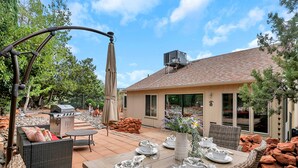 An outdoor patio with a wooden table set for dining, wicker furniture, and a barbecue grill. - Sedona Mountain Trail: A 2BR luxury home in West Sedona with stunning red rock views. (Sedona)