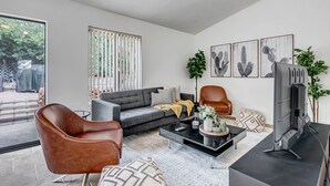 A modern living room with a grey sofa, a brown leather chair, a black coffee table, and a flat-screen TV. - Sedona Mountain Trail: A 2BR luxury home in West Sedona with stunning red rock views. (Sedona)