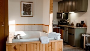 A bathroom with a wooden bathtub, a sink, and a countertop with towels. - Whirlpool Suite w/ Pool, Hot Tub, Hiking, Golfing, & More on Lutsen Mountain (Tofte)