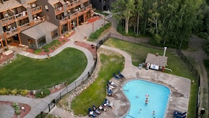 A multi-story hotel with a swimming pool, outdoor seating, and a landscaped garden. - Whirlpool Suite w/ Pool, Hot Tub, Hiking, Golfing, & More on Lutsen Mountain (Tofte)