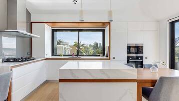 A modern kitchen with a large window, white cabinetry, and a marble countertop.