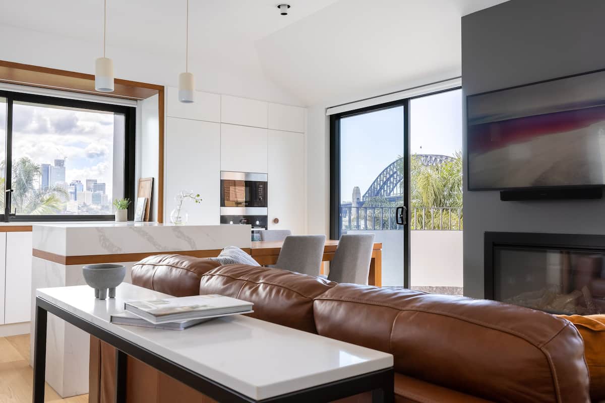 A modern living room with a leather sofa, a dining area, and a kitchen.