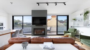 Un salon moderne avec un canapé en cuir, une table basse blanche et une cheminée.